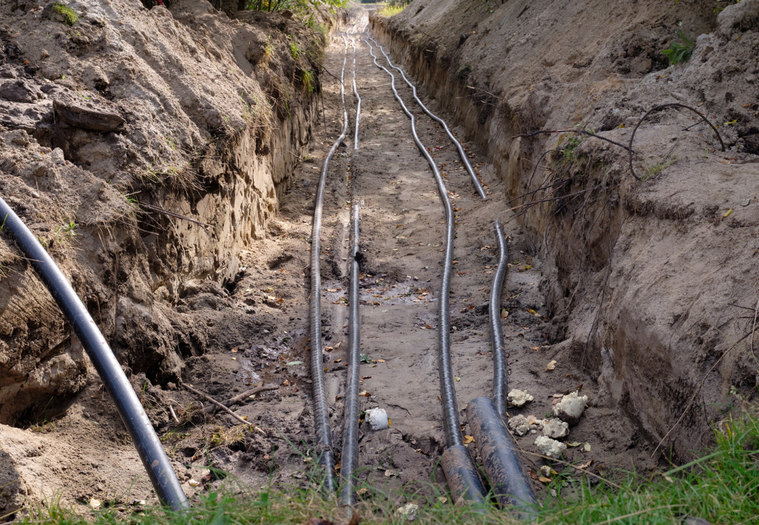 Cables laid in a narrow dirt trench.