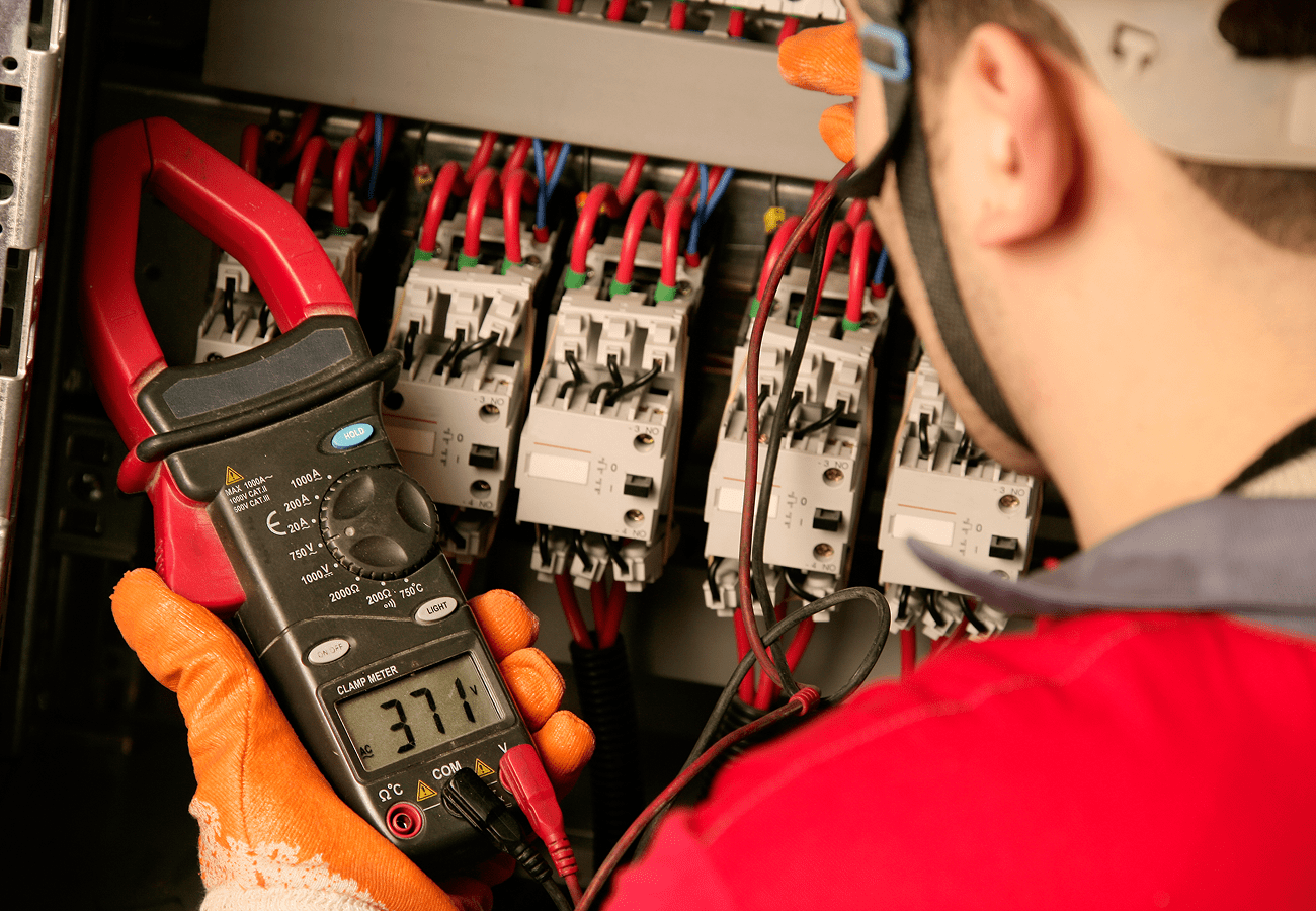 Electrician using multimeter on circuit board.