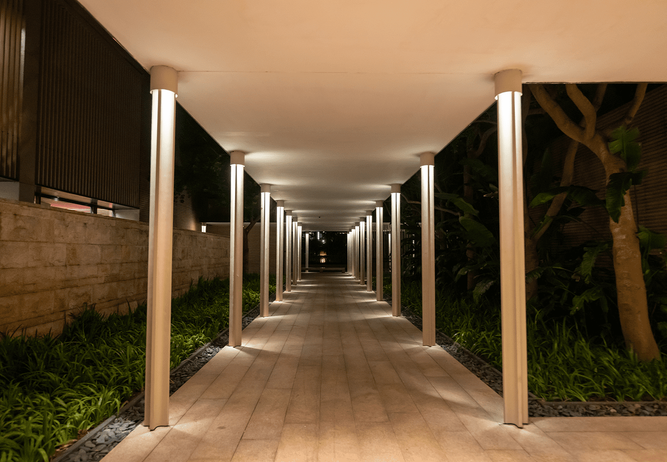Illuminated covered walkway with columns at night.