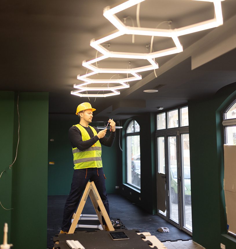 Electrician installing lights in modern interior.